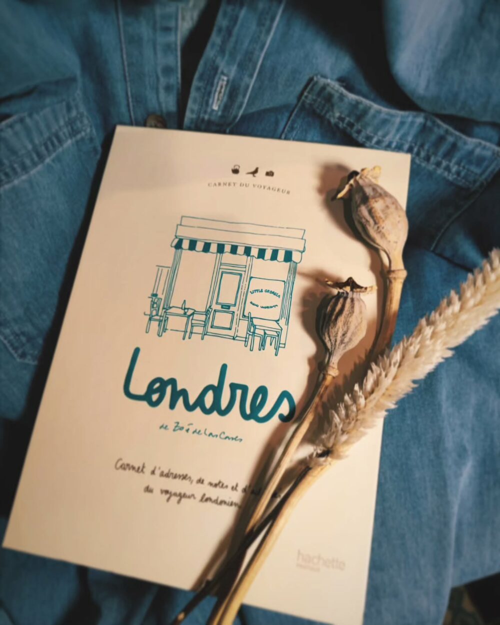 Carnet de voyage "Londres" posé sur une veste en jean avec des fleurs séchées