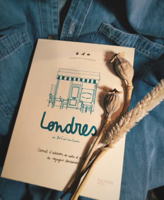 Carnet de voyage "Londres" posé sur une veste en jean avec des fleurs séchées