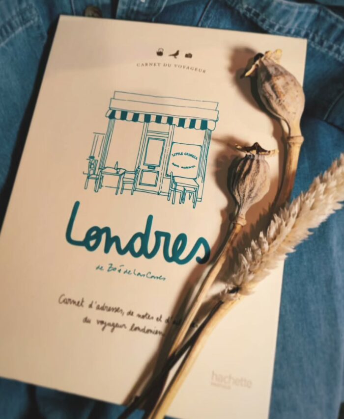 Carnet de voyage "Londres" posé sur une veste en jean avec des fleurs séchées