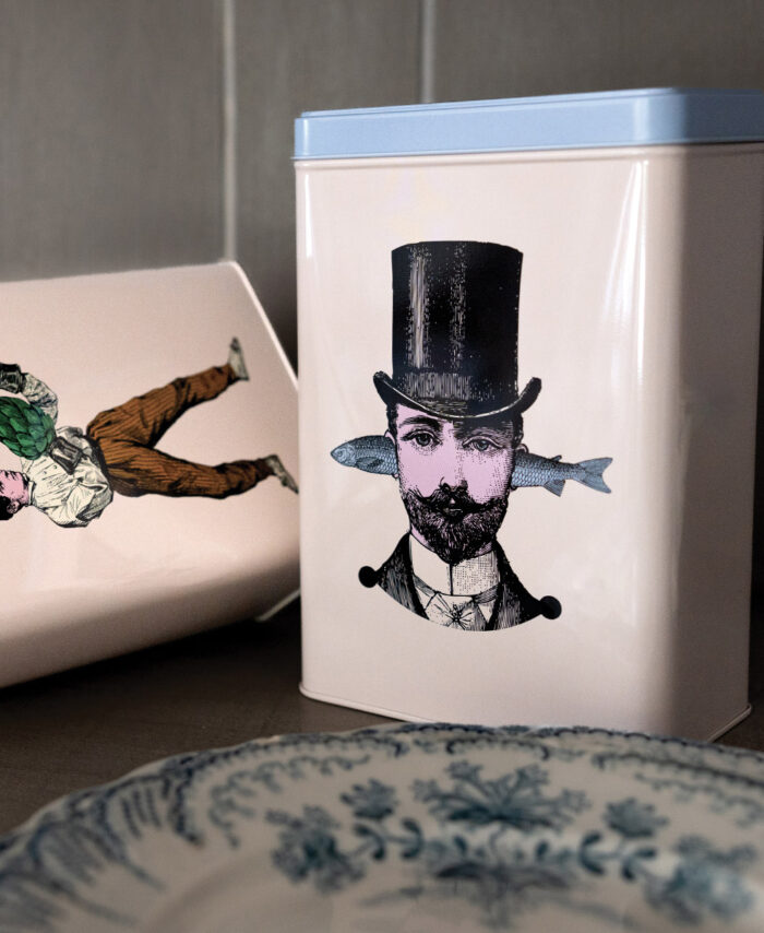 Boîte en métal Gangzaï avec couvercle bleu clair, ornée d’une illustration surréaliste d’un homme barbu portant un haut-de-forme noir et un poisson traversant sa tête.