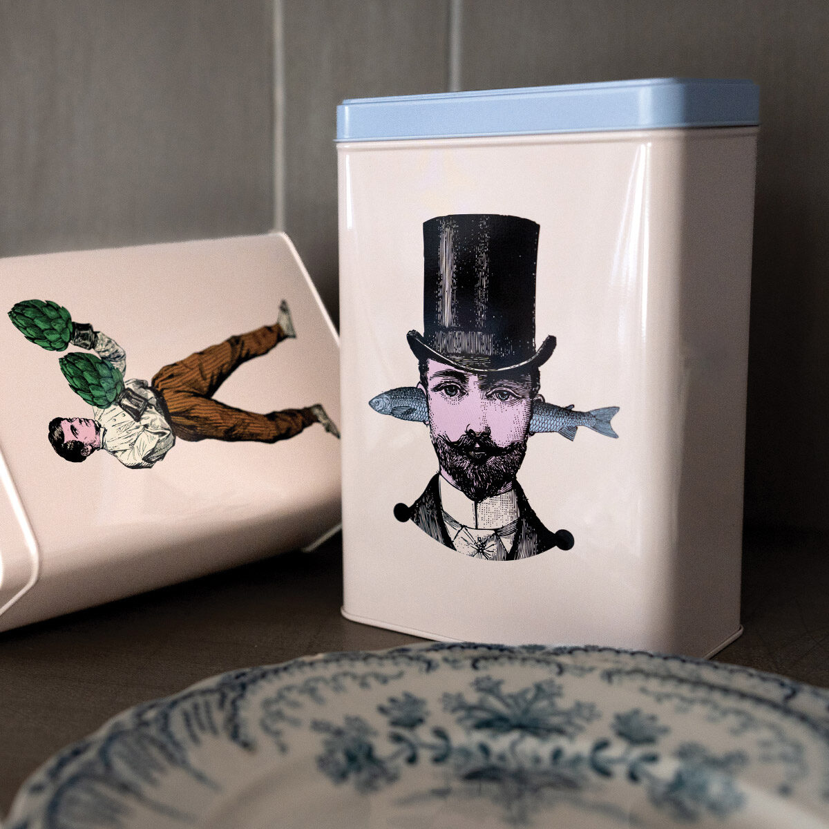 Boîte en métal Gangzaï avec couvercle bleu clair, ornée d’une illustration surréaliste d’un homme barbu portant un haut-de-forme noir et un poisson traversant sa tête.